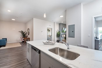 Millside kitchen island with dishwasher and stainless sink and white granite counter